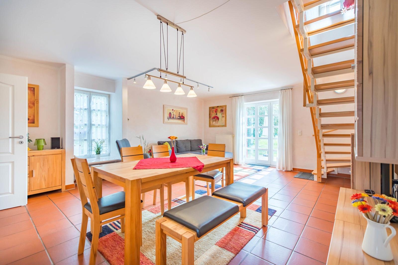 Esszimmer mit Holztisch, Stühlen und Treppe zur oberen Etage.