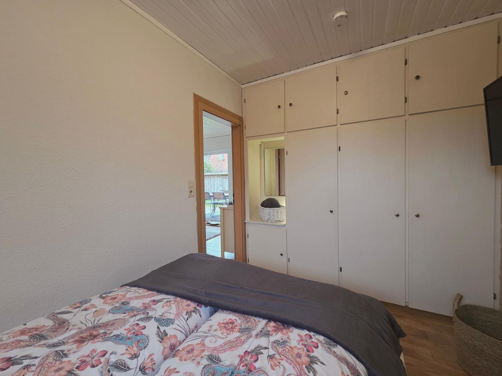 Schlafzimmer mit Bett, Schränken und Tür zum Balkon.