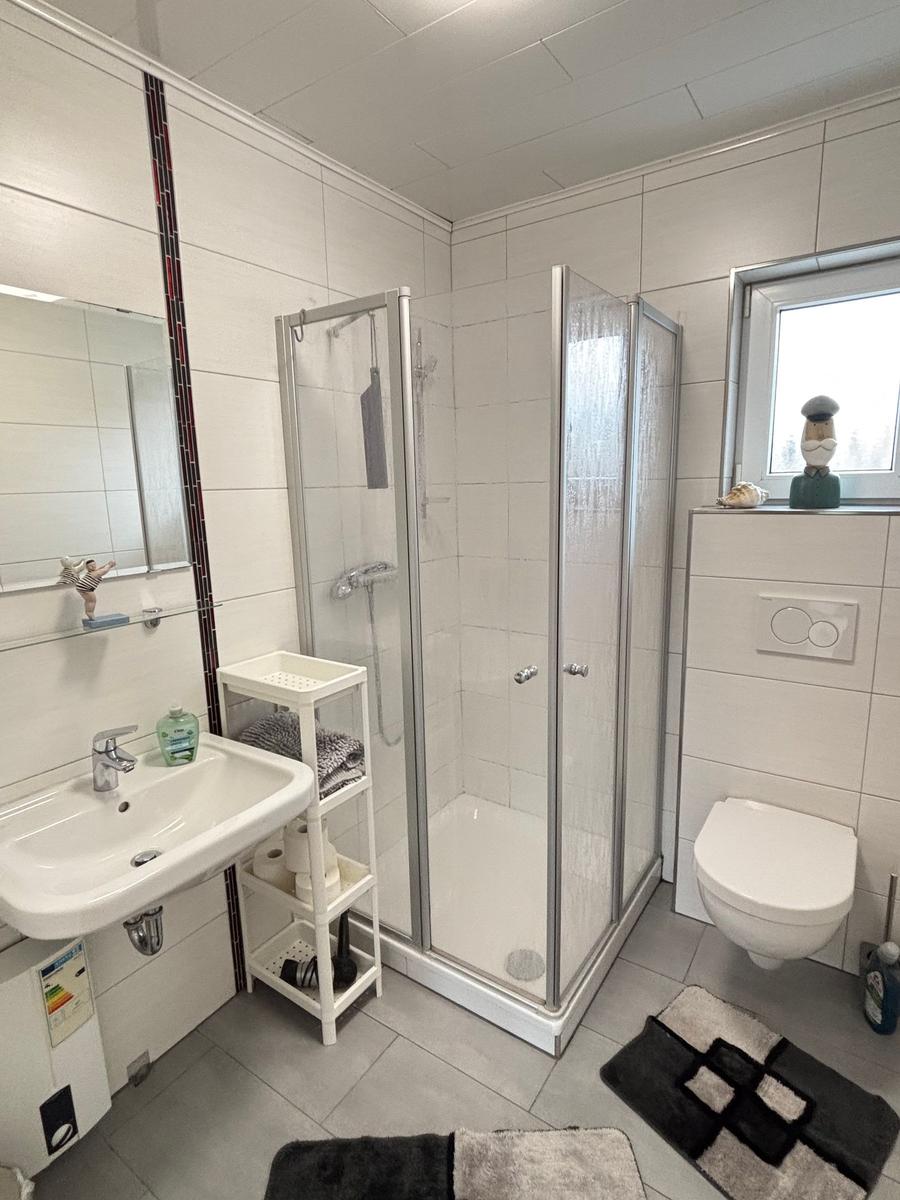Badezimmer mit Dusche, Waschbecken und Toilette.