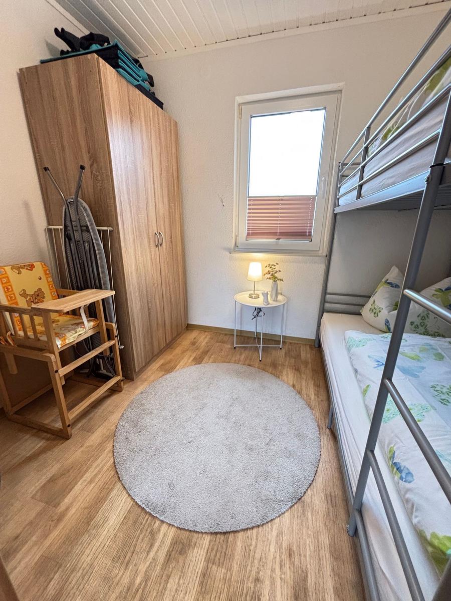 Zimmer mit Doppelstockbett, Kleiderschrank und Rundteppich.
