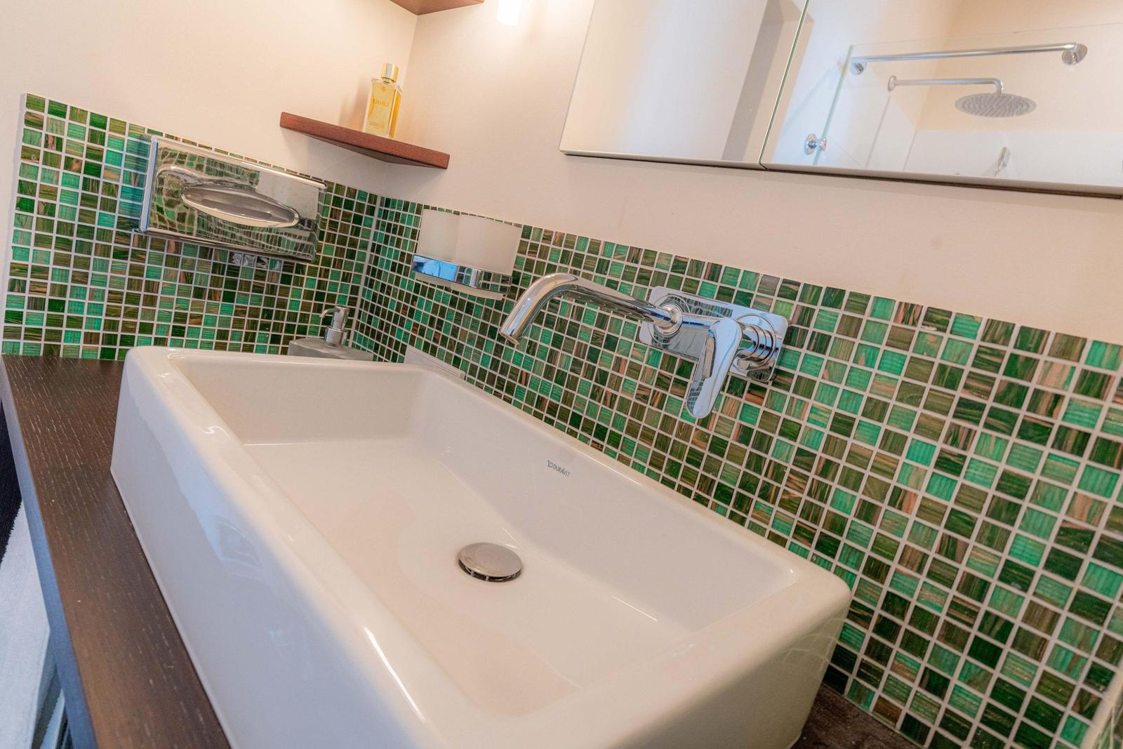 Waschbecken mit grünem Fliesenspiegel und Spiegel