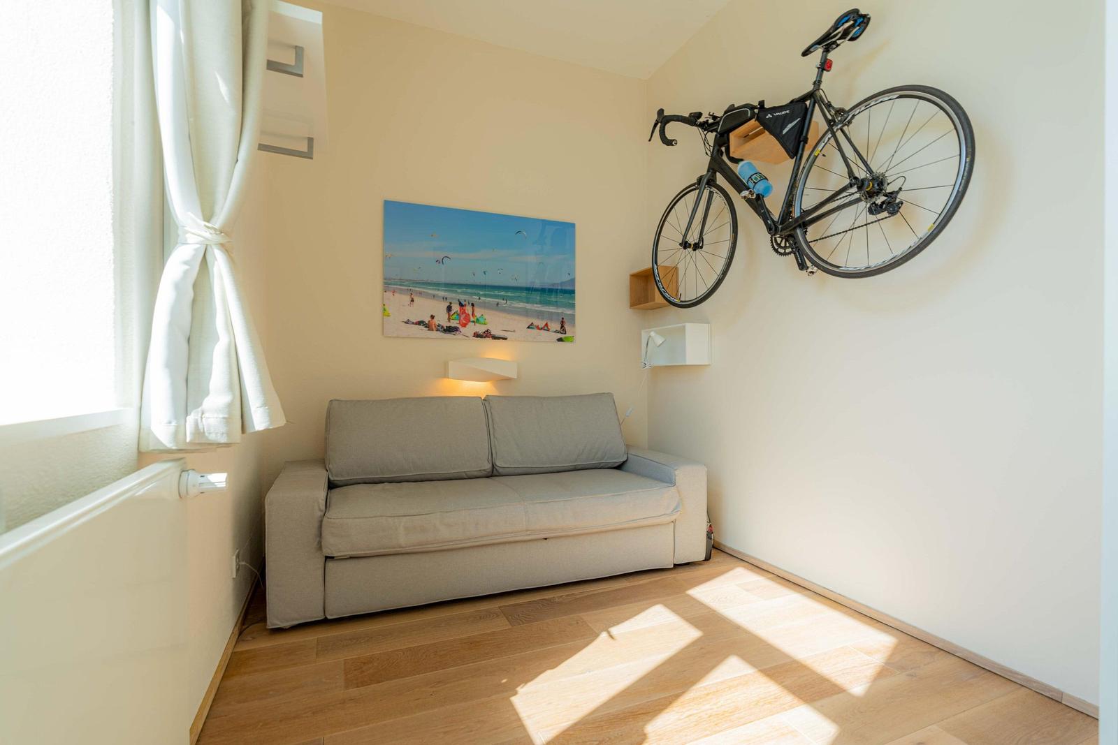 Ein Raum mit Sofa, Wandbild und aufgehängtem Fahrrad.