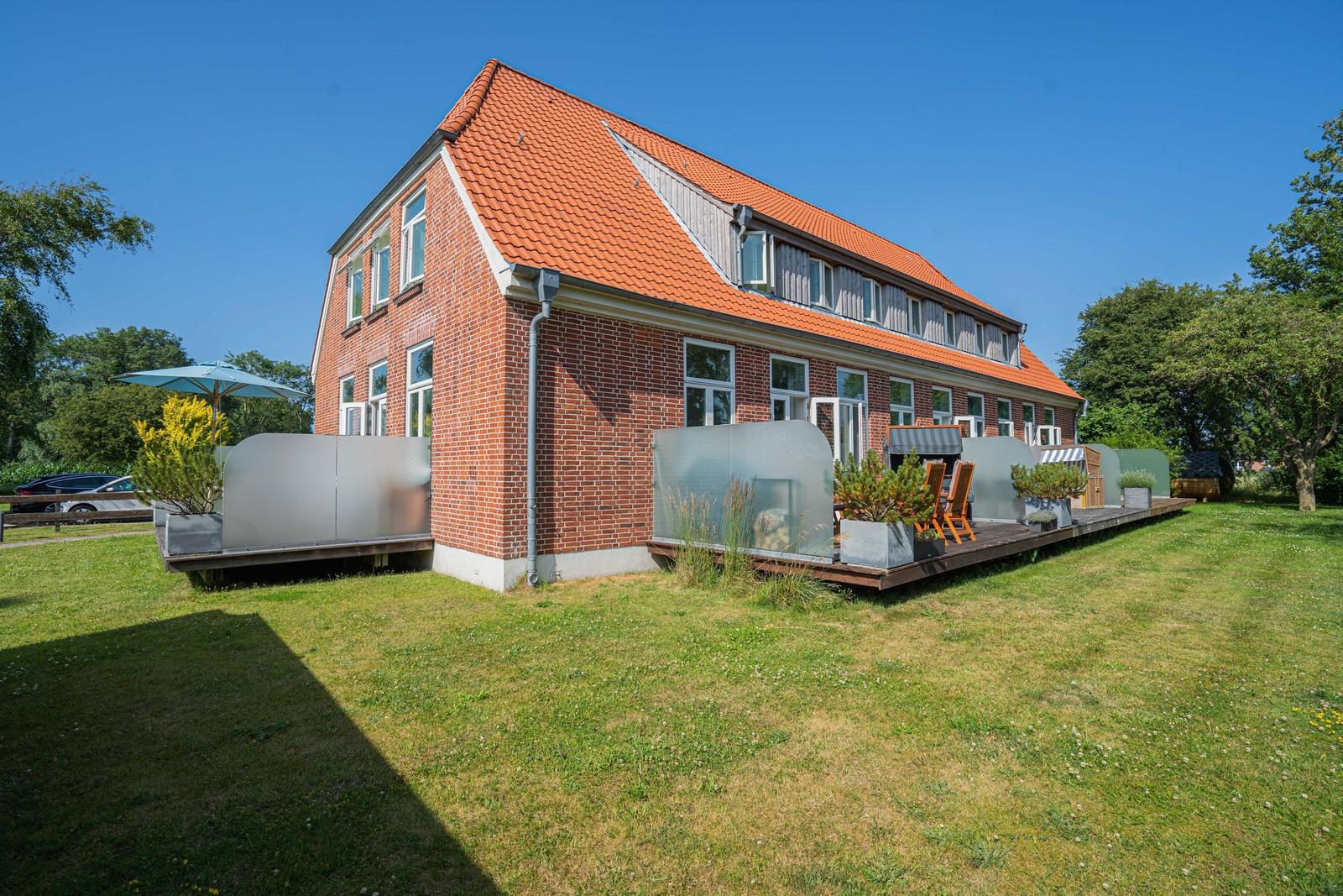 Rotes Ziegelhaus mit Terrasse und Garten. Moderne Pavillons und Sitzgelegenheiten.
