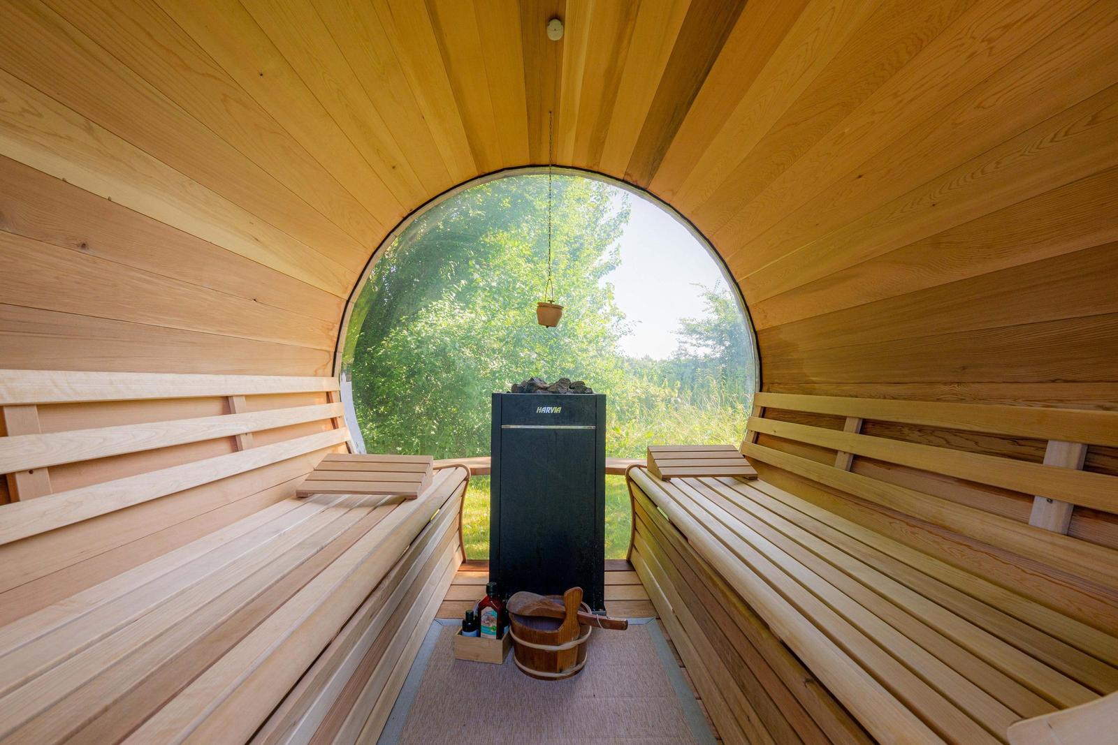 Sauna mit Holzbänken und runden Fensterblick auf Grün