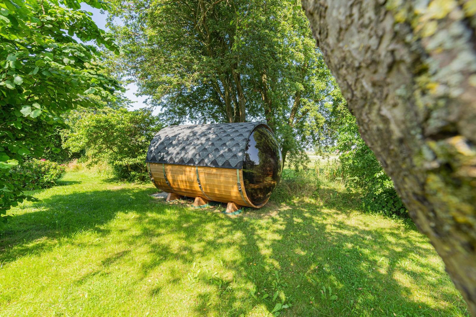 Holz-Kuppelhaus mit Dach auf grünem Rasen zwischen Bäumen