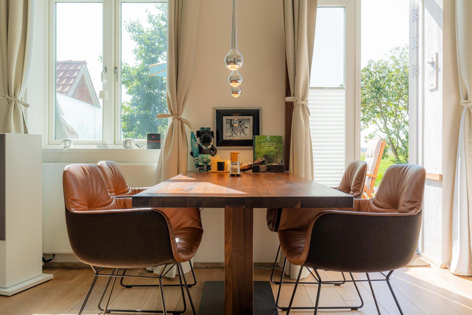 Esszimmer mit Holztisch, Ledersitzen und großen Fenstern zur Aussicht.