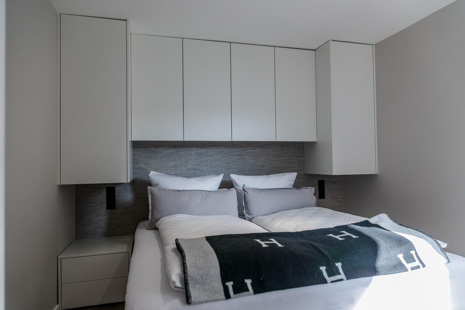 Schlafzimmer mit Bett, Kopfteil und integrierten Schränken.