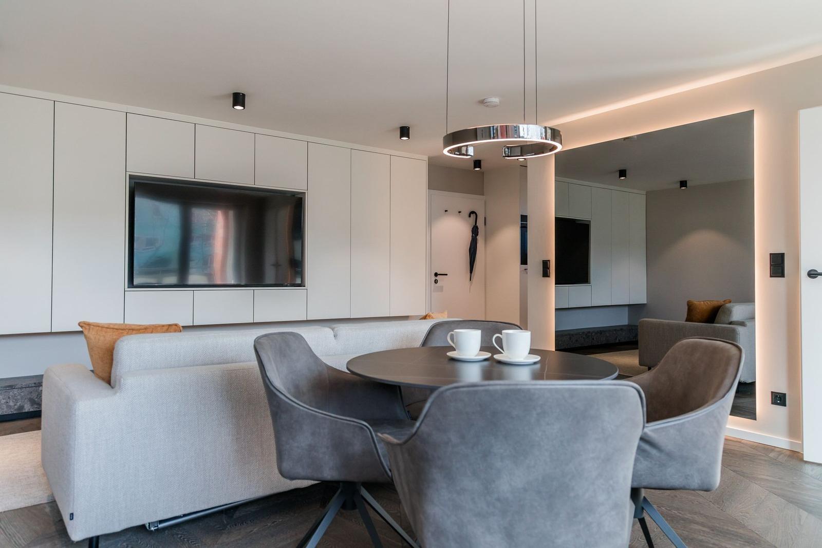 Modern eingerichtetes Wohn- und Esszimmer mit TV, Tisch und Stühlen.