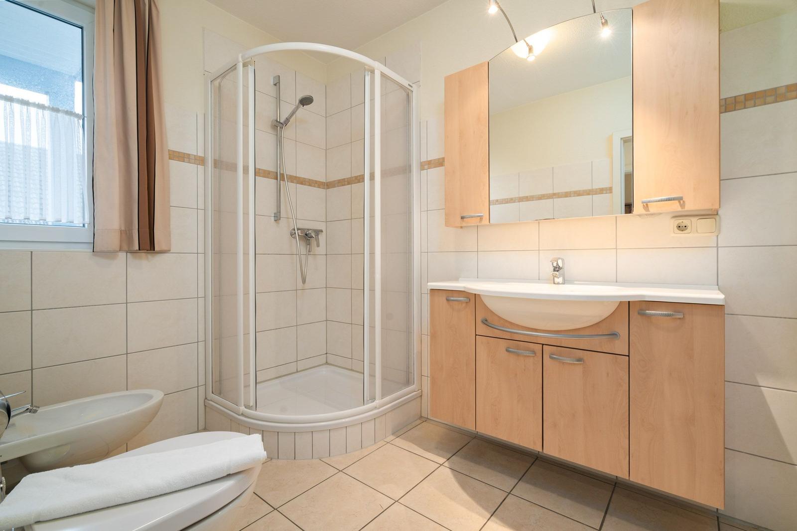 Badezimmer mit Dusche, Waschbecken und Toilette.