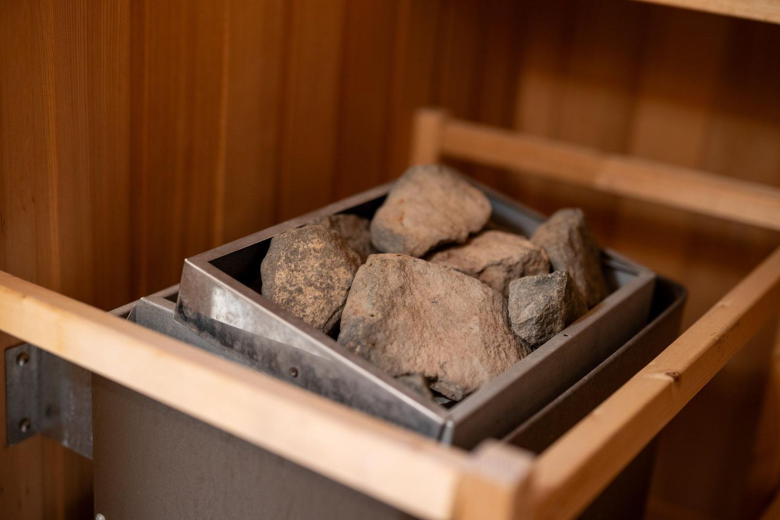 Steine in einem Metallbehälter in einer Holzsauna