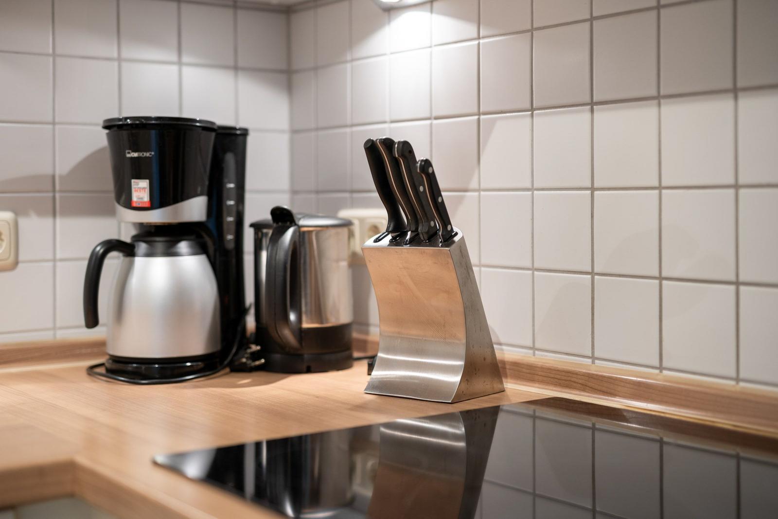 Küchenzeile mit Kaffeemaschine, Wasserkocher und Messerblock.