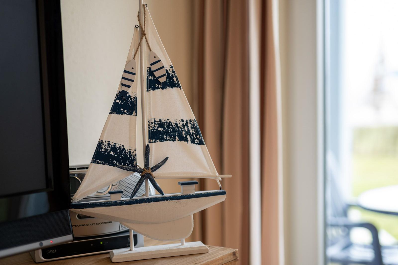 Ein Segelschiffmodell mit Segeln und Sternfisch steht auf einem Holztisch.