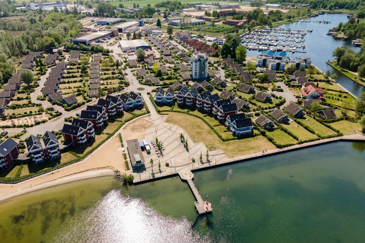 Aerial view of residential area near water with marina and green spaces.