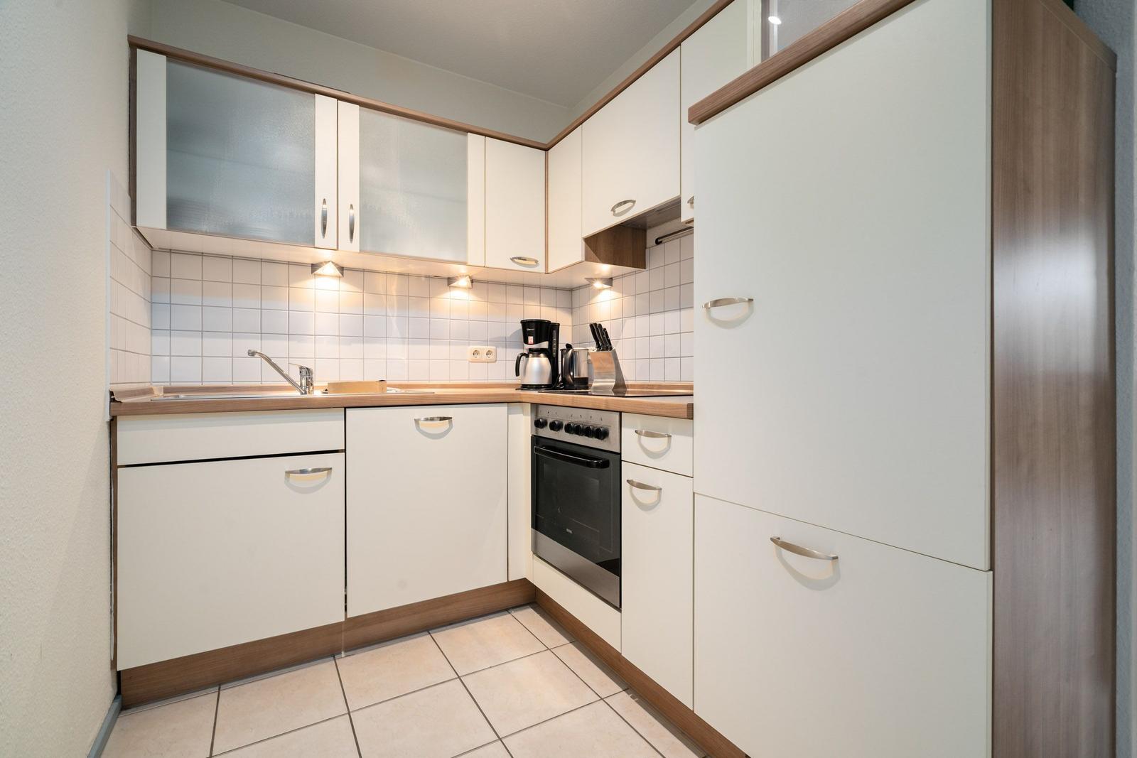 Küche mit weißen Schränken, Holzoberflächen und integriertem Ofen.