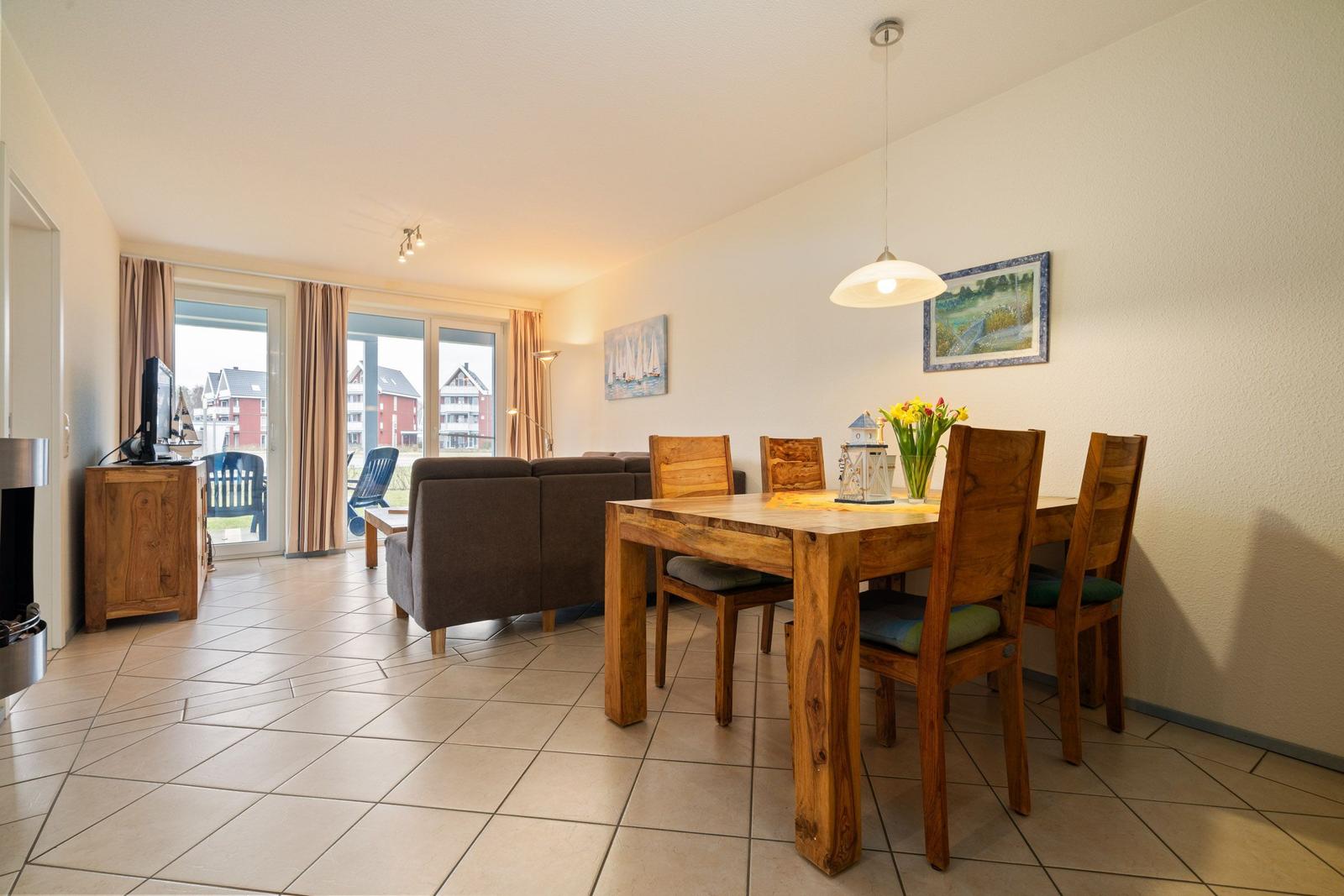 Wohn- und Essbereich mit Holztisch, Sofa und Blick auf Terrasse.