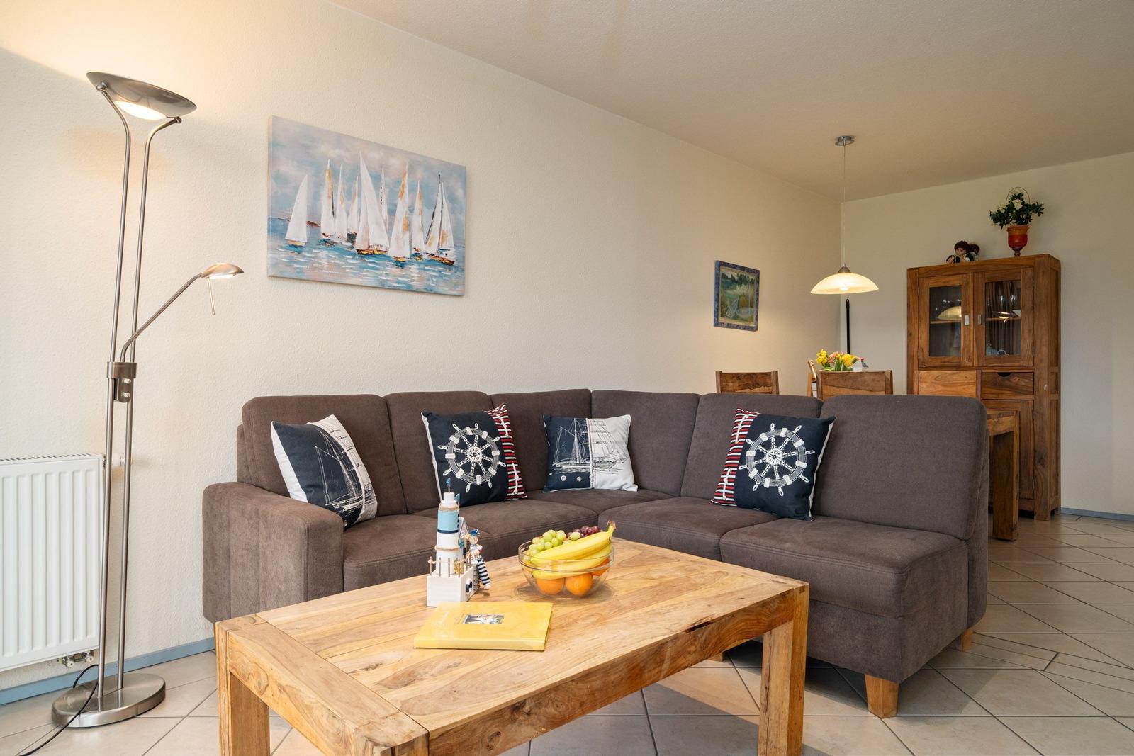 Wohnzimmer mit Sofa, Holztisch und Segelboot-Bild an der Wand.