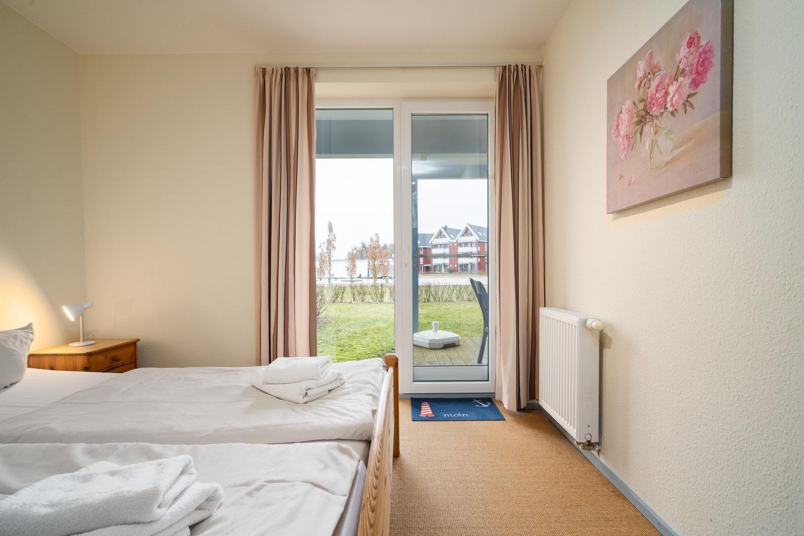 Schlafzimmer mit Doppelbett, Blick auf Terrasse und Garten.