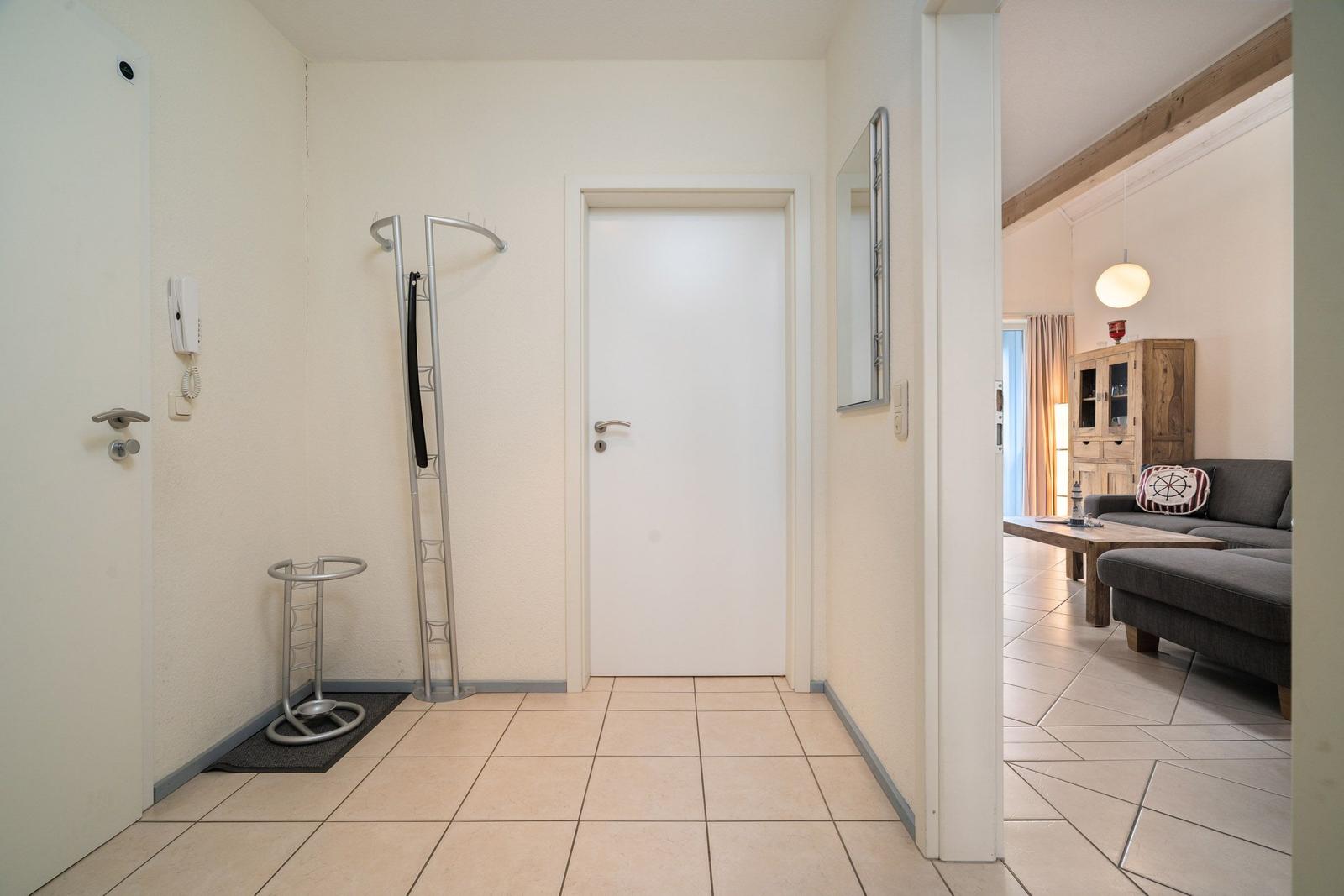 Flur mit Garderobe und Blick in Wohnbereich mit Sofa und Tisch