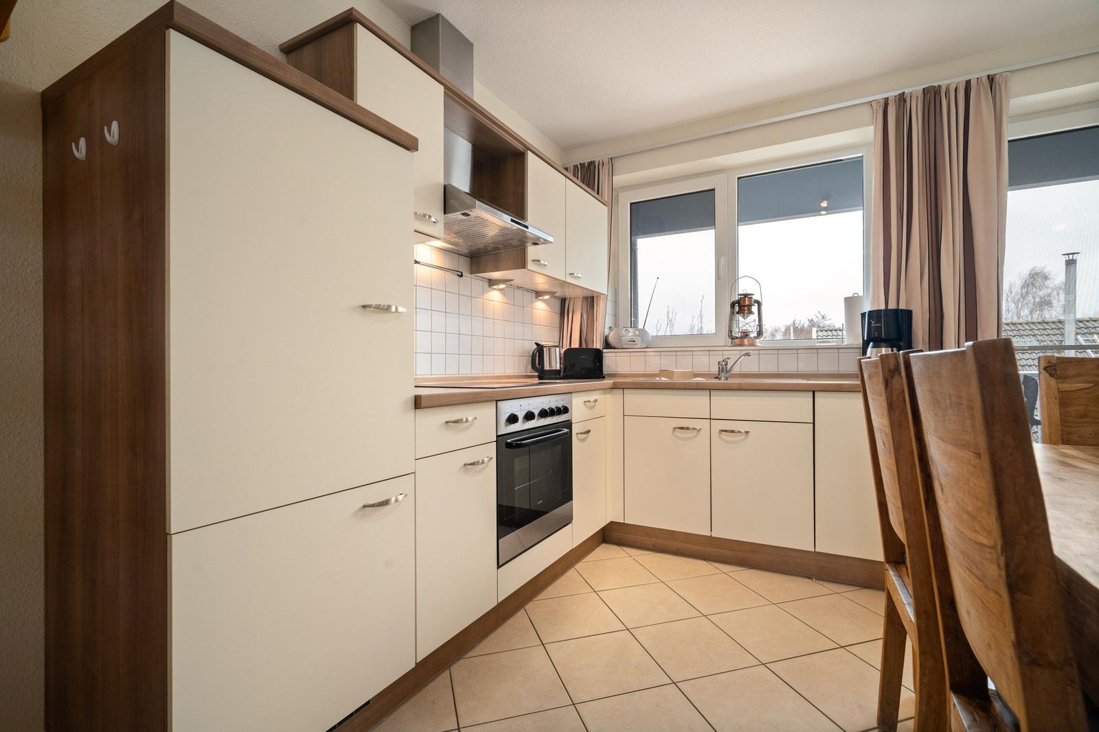 Küche mit Holzschrank, Herd und Fenster