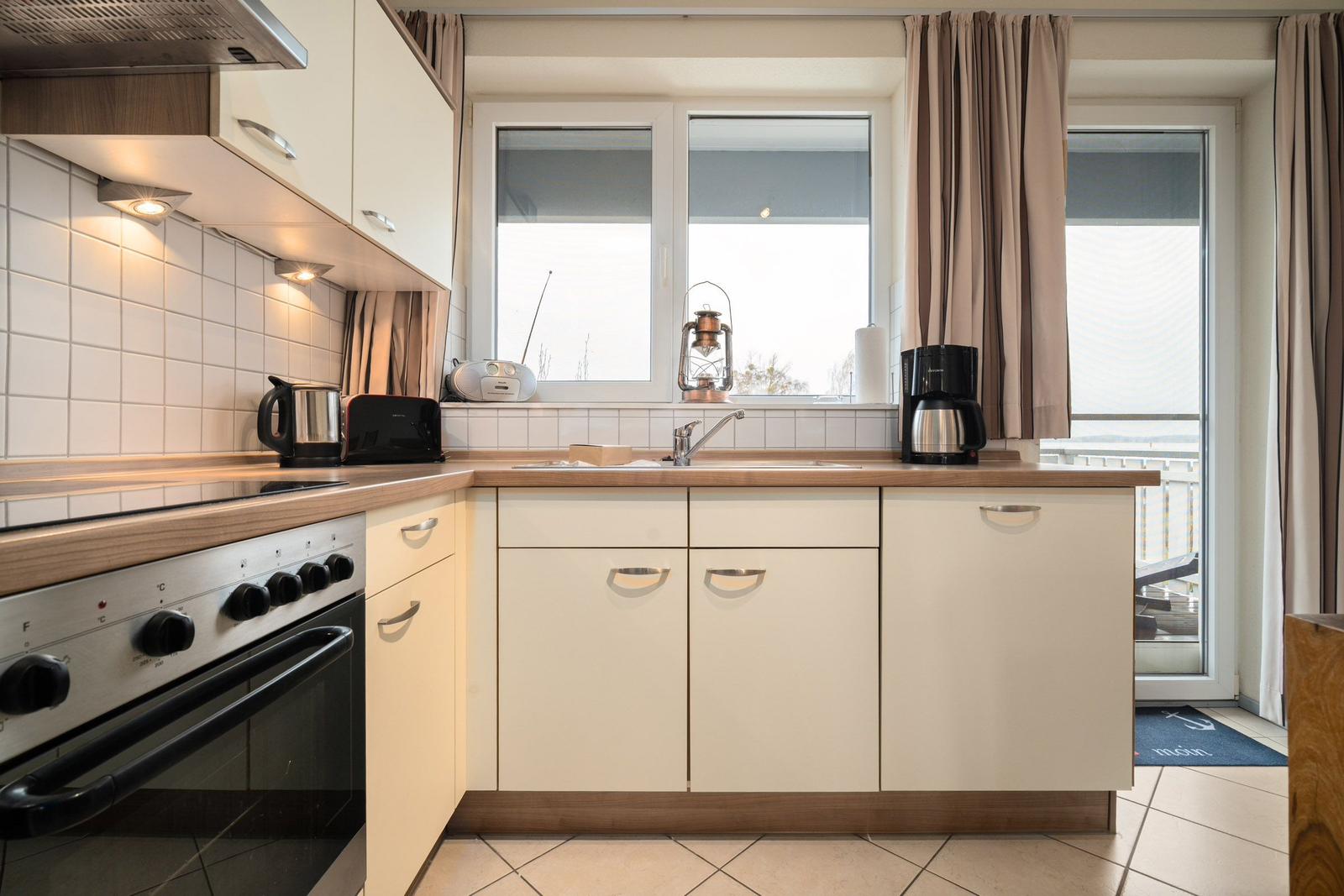 Küche mit Arbeitsfläche, Spüle und Fenster zur Terrasse.