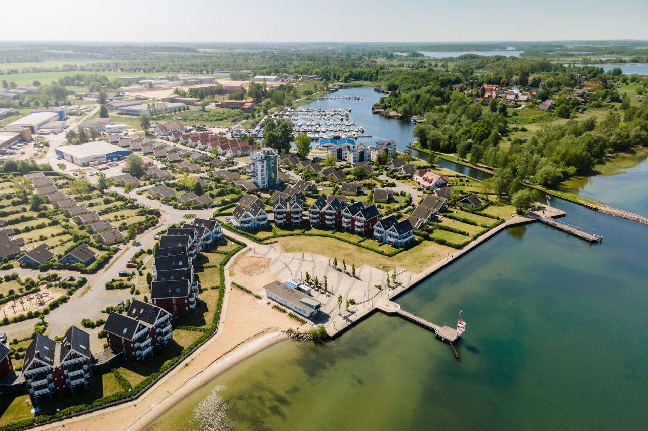 Aerial view of a waterfront residential area with houses, docks, and a marina.