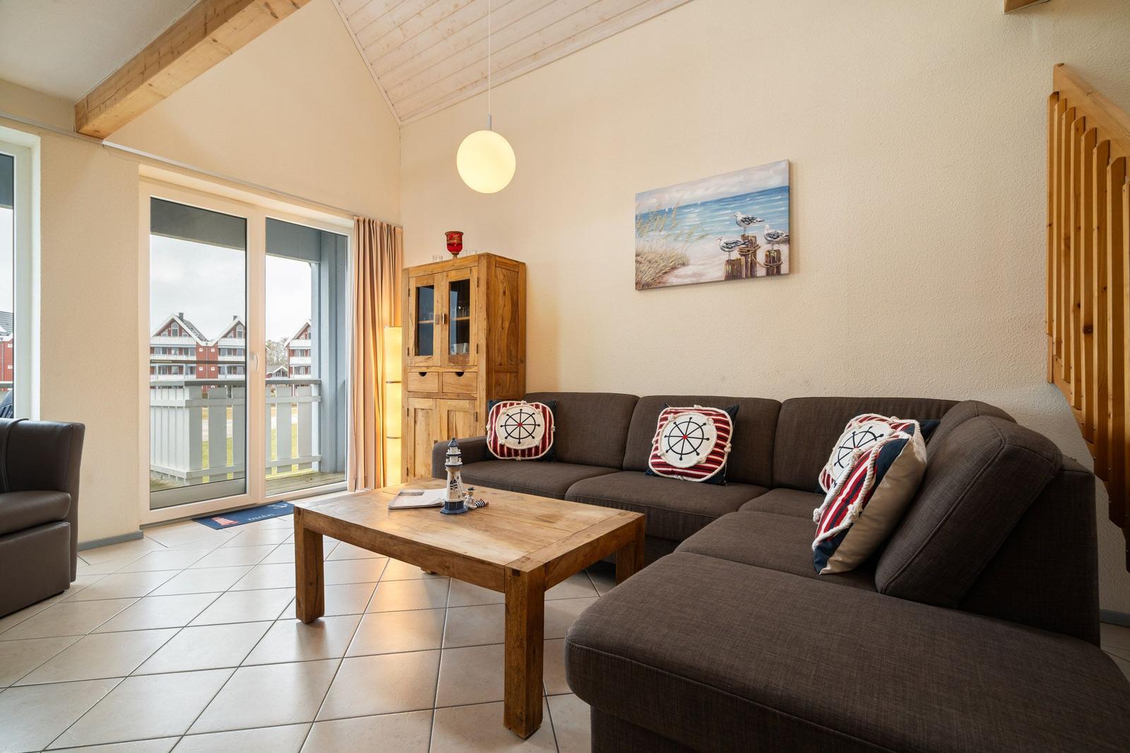 Wohnzimmer mit Sofa, Couchtisch und Balkontür. Wandbild und Holzregal sichtbar.