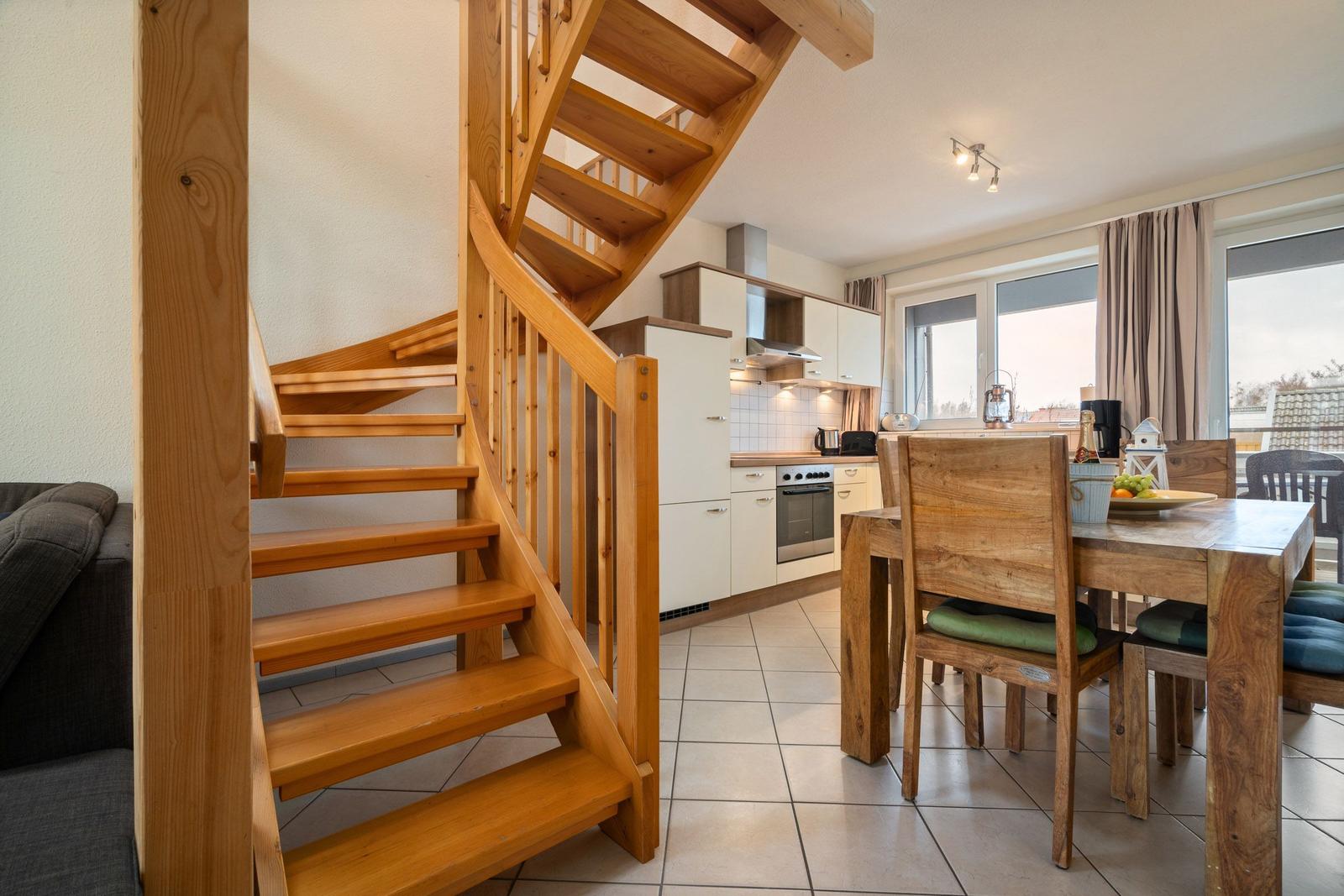 Holztreppe führt zur Küche und Esszimmer mit Tisch und Stühlen.