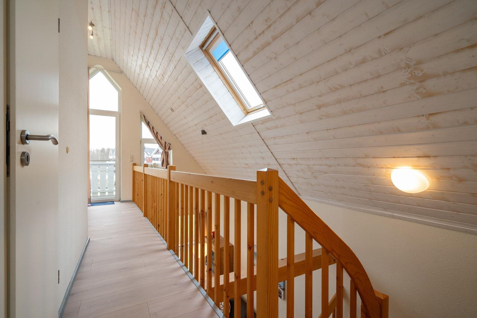 Haus mit Holzverkleidung, Dachfenster und Holzgeländer im Flur