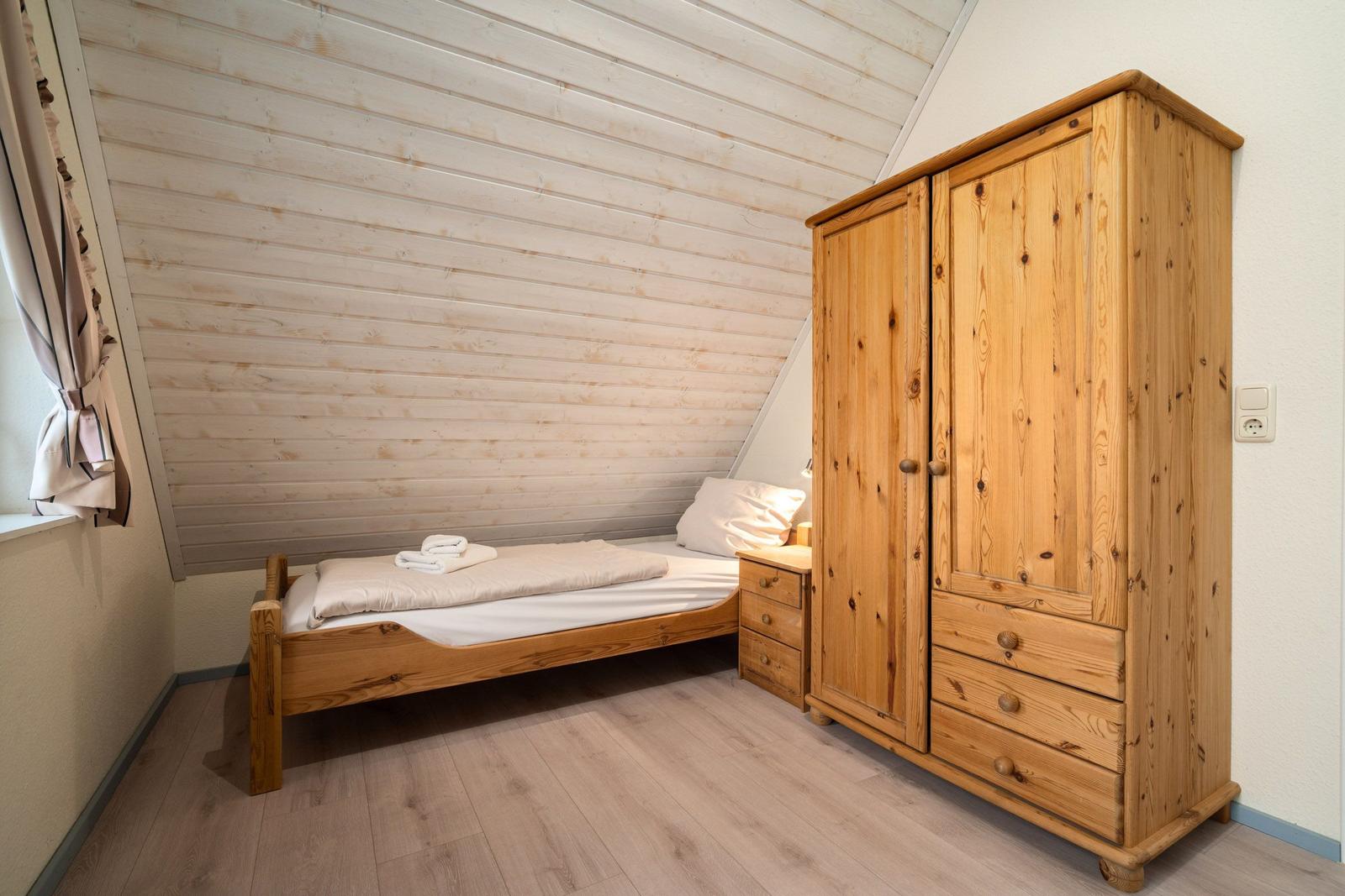 Schlafzimmer mit Holzbett, Kleiderschrank und Holzwand