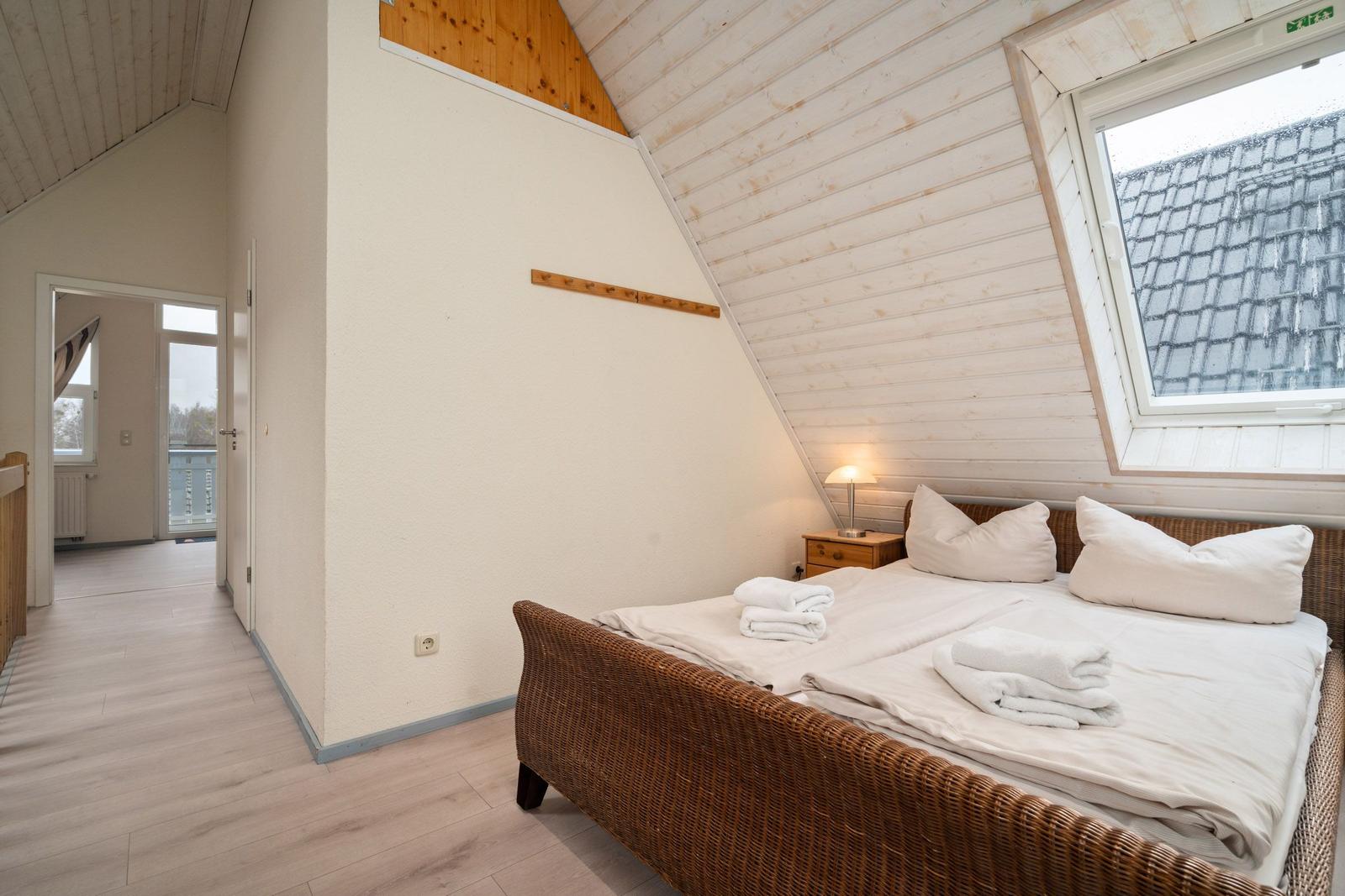 Schlafzimmer mit Dachschrägen, Bett und Fenster.