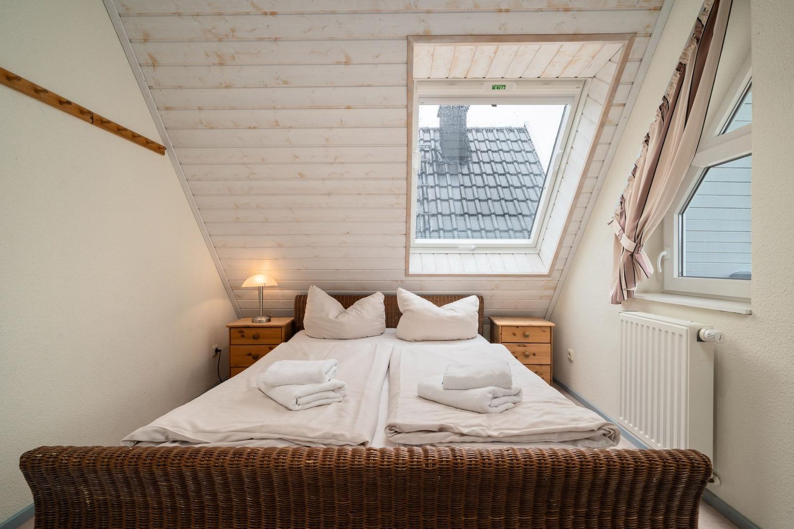 Schlafzimmer mit Dachfenster, Bett und Nachttischen