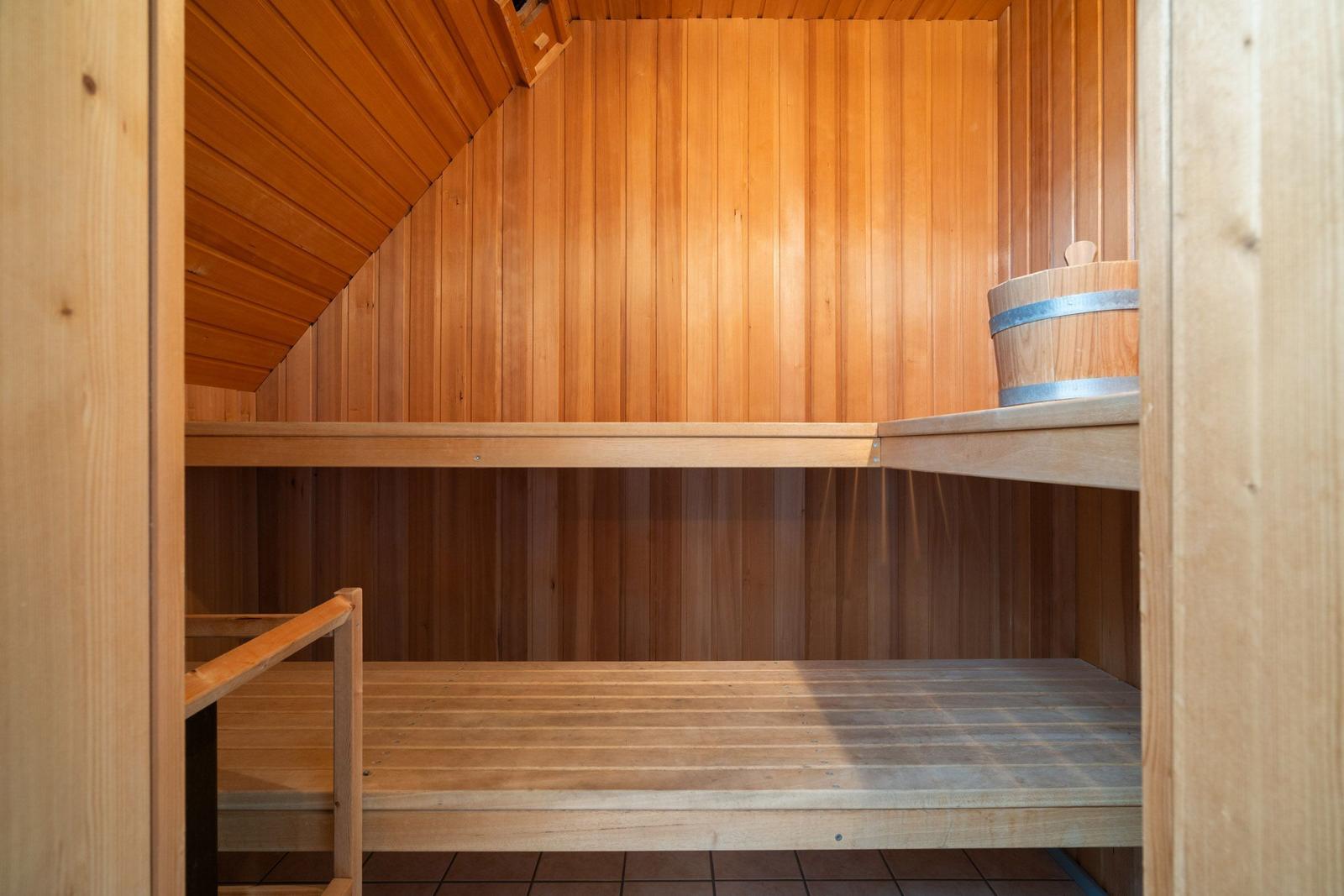 Sauna mit Holzwand, Sitzbänken und Eimer