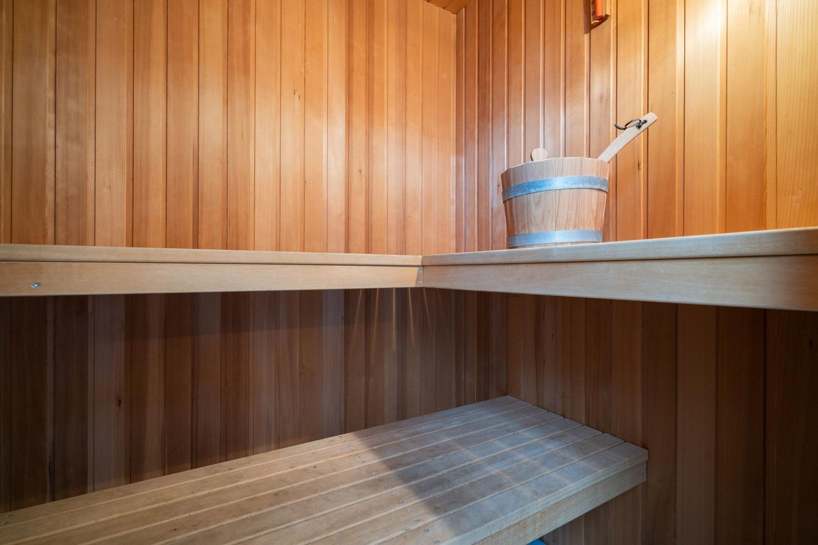 Sauna mit Holzwand, Sitzbank und Eimer mit Löffel