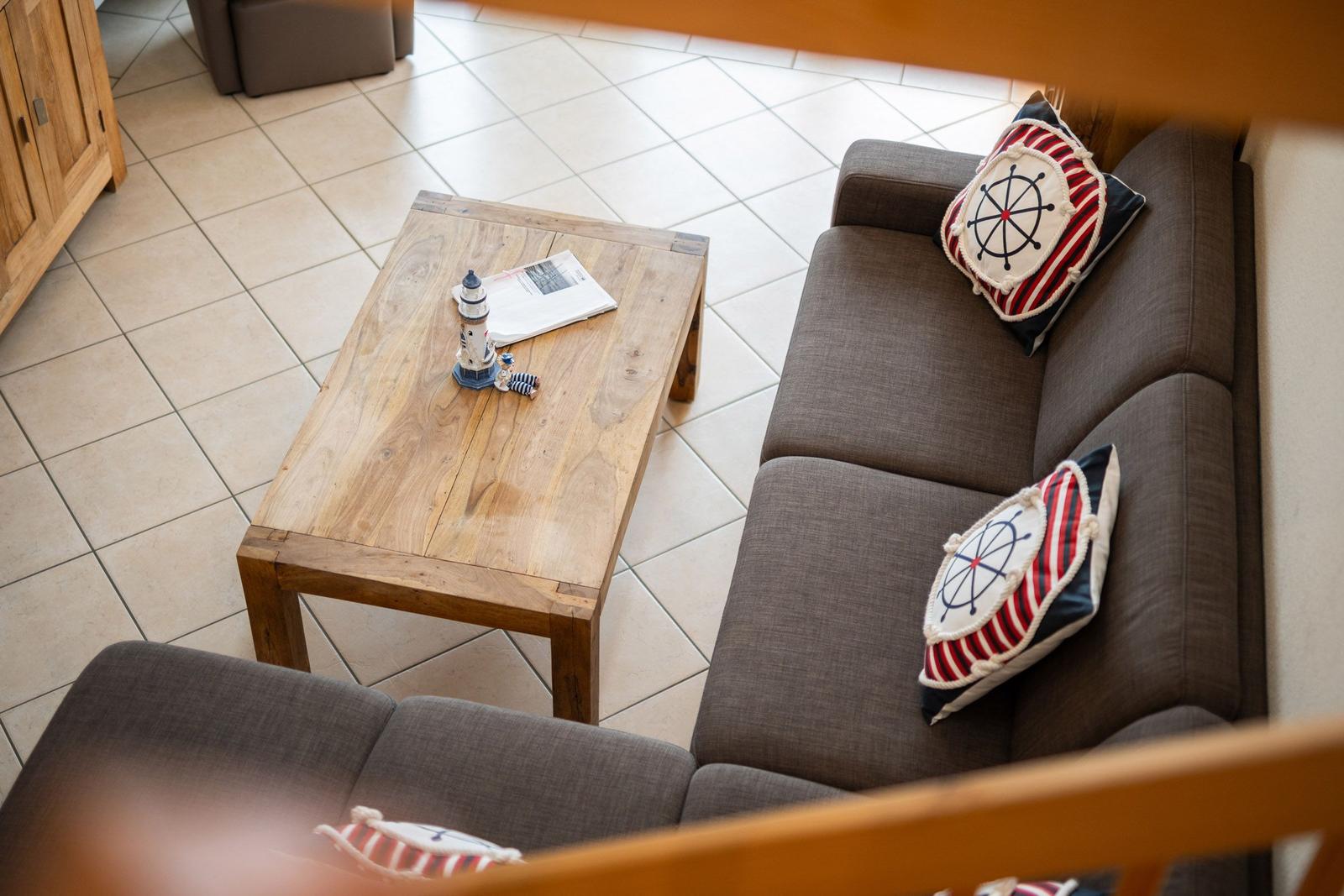 Ein Sofa mit Kissen und einem Holztisch mit Lighthouse-Modell.