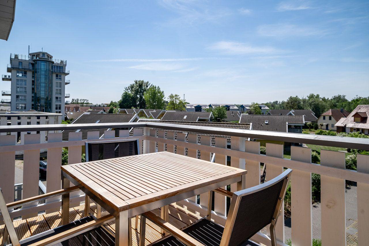 Terrasse mit Tisch und Stühlen, Blick auf Wohnhäuser und einen Turm.