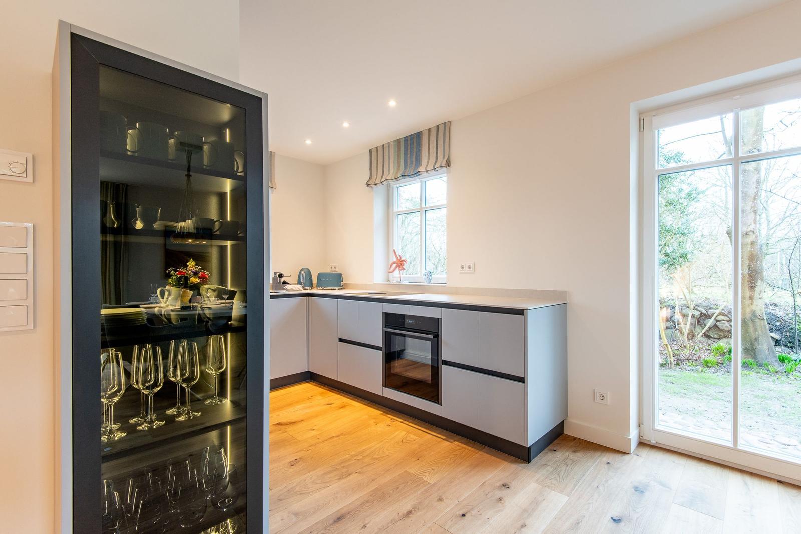 Küche mit Glasvitrine, Holzboden und Fenster zum Garten