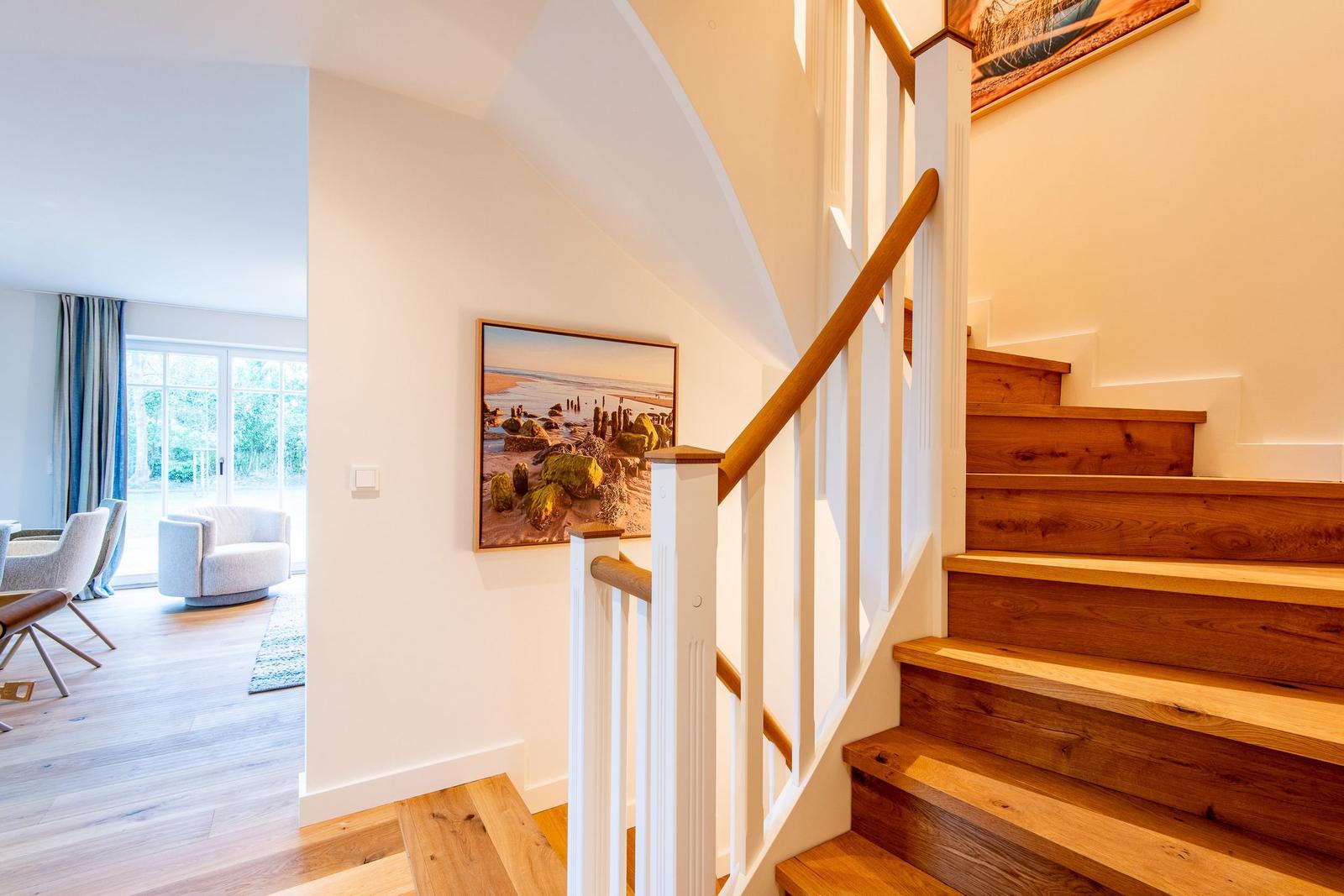Hölzerner Treppenaufgang mit weißer Balustrade und Wandbildern