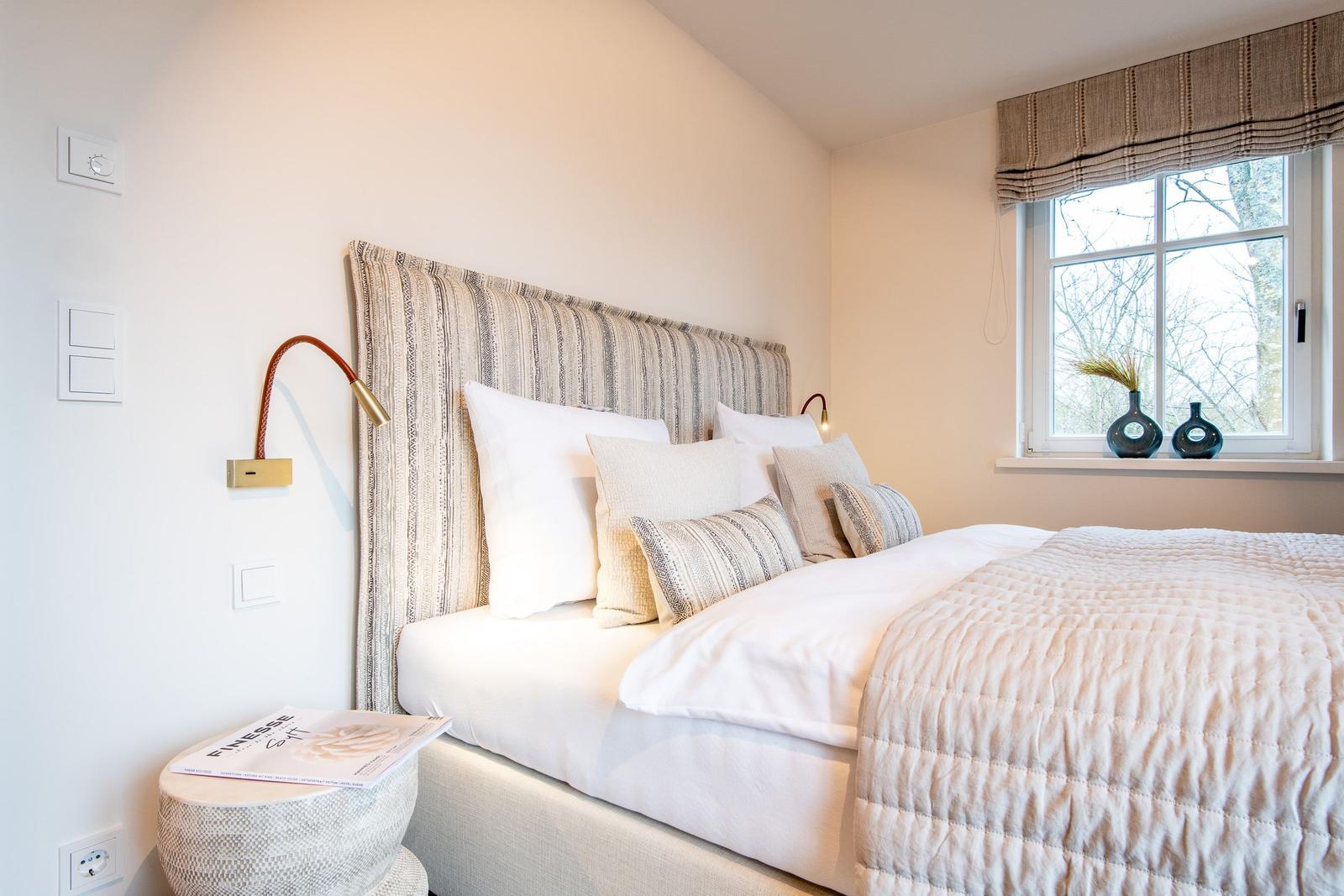 Schlafzimmer mit Bett, Fenster und Nachttisch.