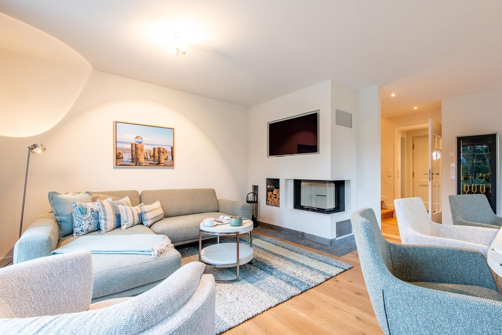 Wohnzimmer mit Sofa, Sesseln, Kamin und Fernseher.