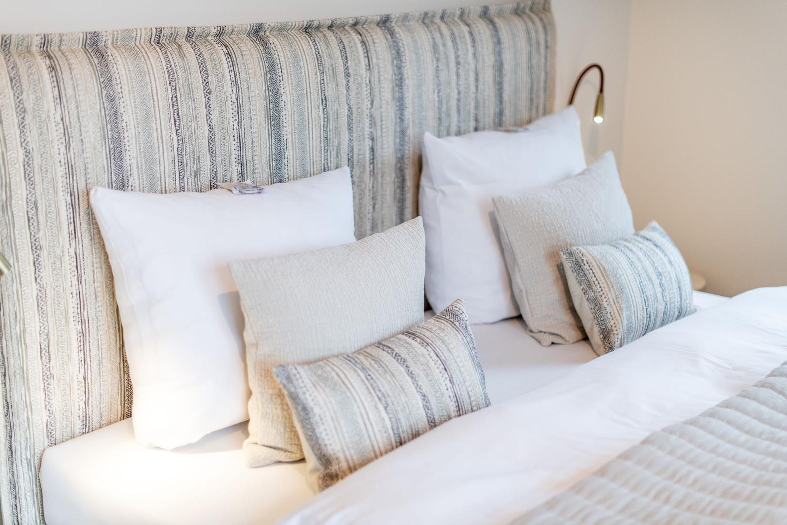 Bettkopfteil mit gemustertem Stoff und Kissen in verschiedenen Farben und Mustern.