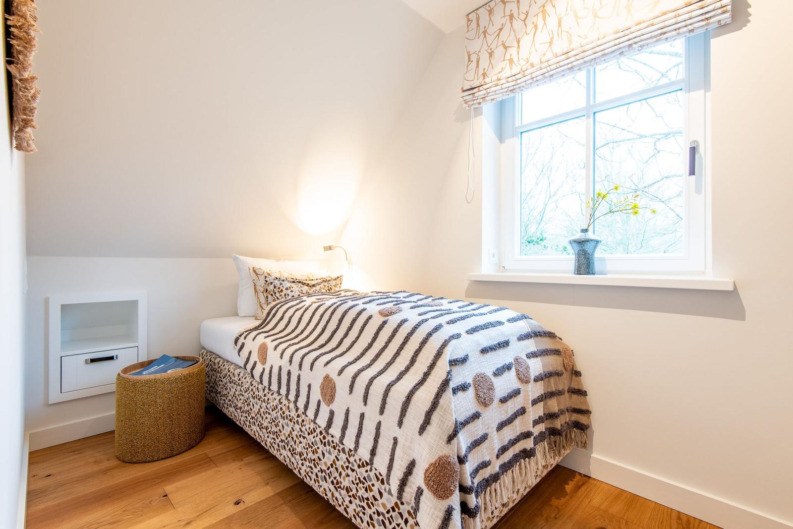 Ein Schlafzimmer mit Bett, Fenster und Holzboden.