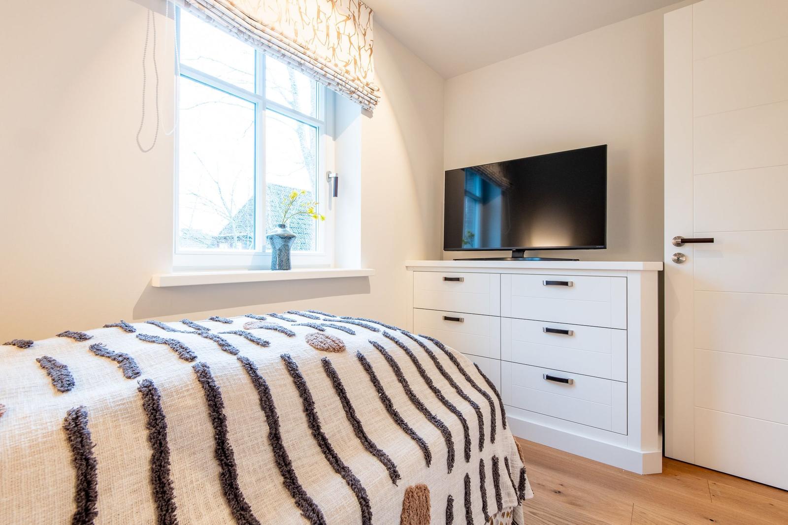 Schlafzimmer mit Bett, Fernseher und Fenster