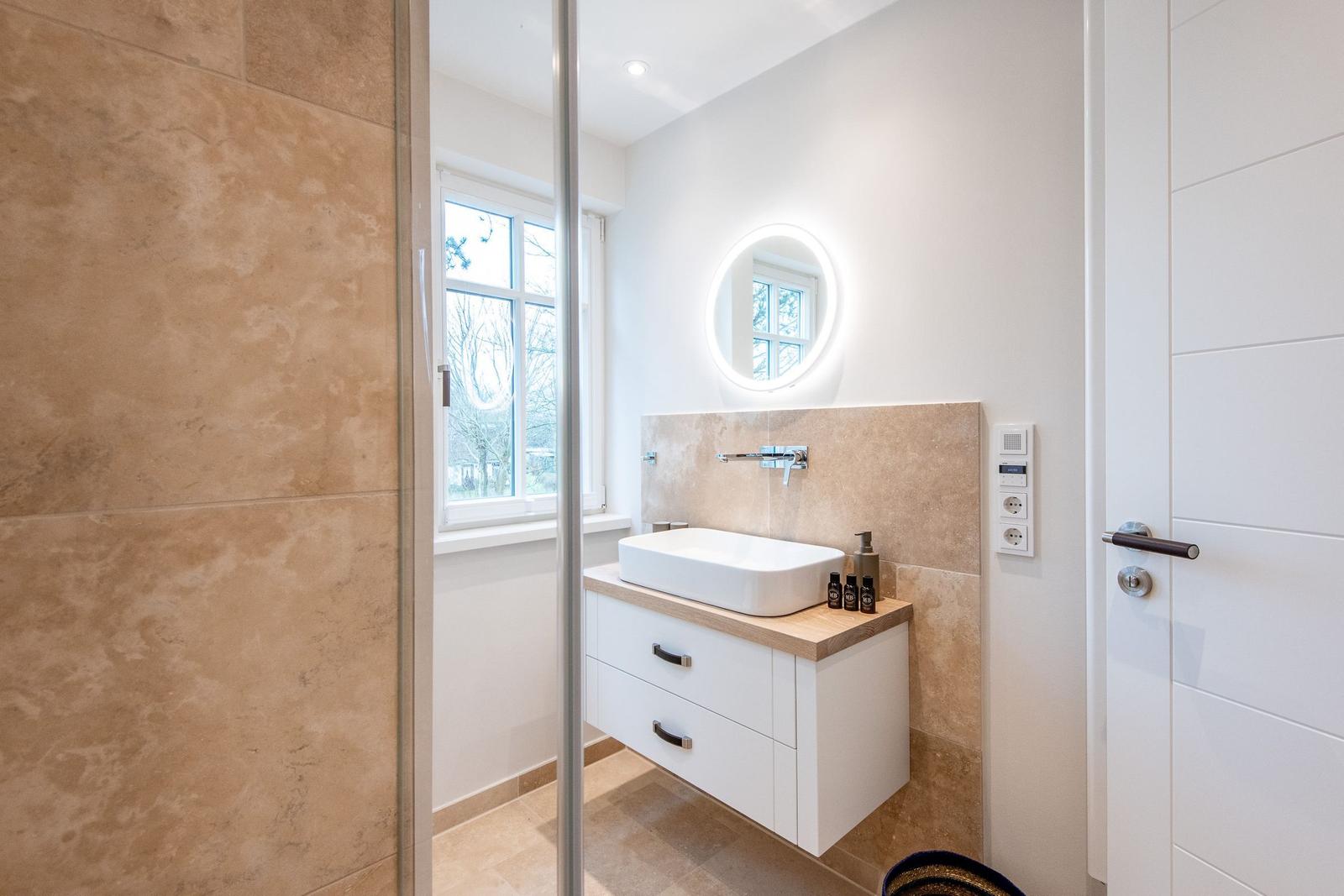 Badezimmer mit Waschbecken, Spiegel und Fenster.