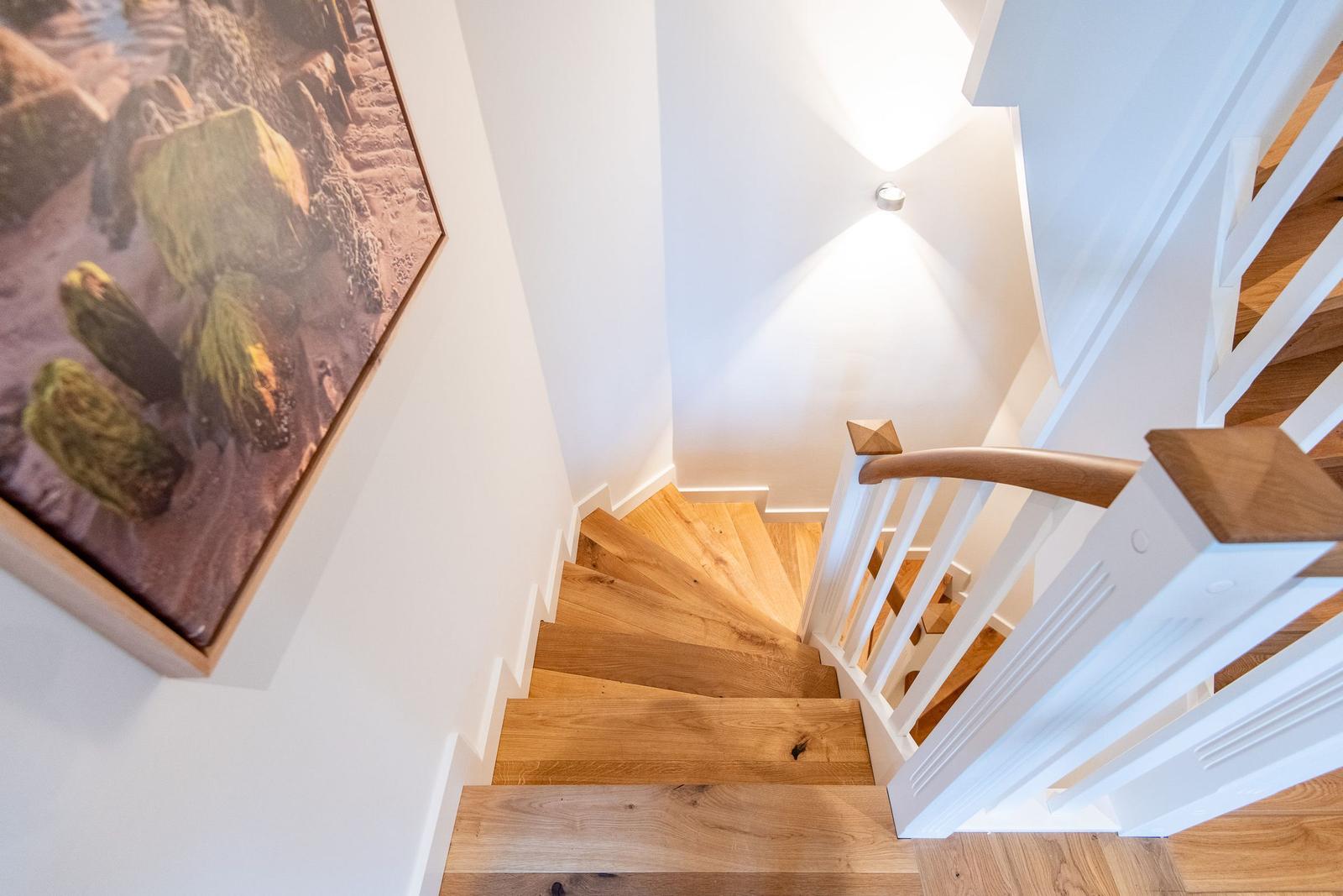 Holzgetriebene Treppe mit weißer Balustrade und Wandbild
