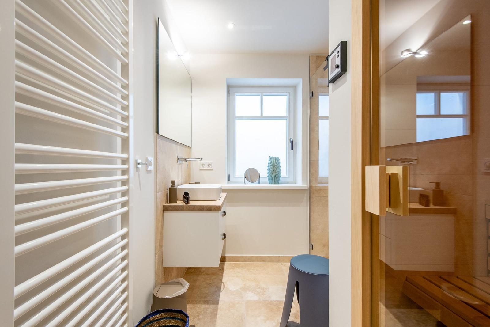 Badezimmer mit Dusche, Waschbecken und Heizkörper.