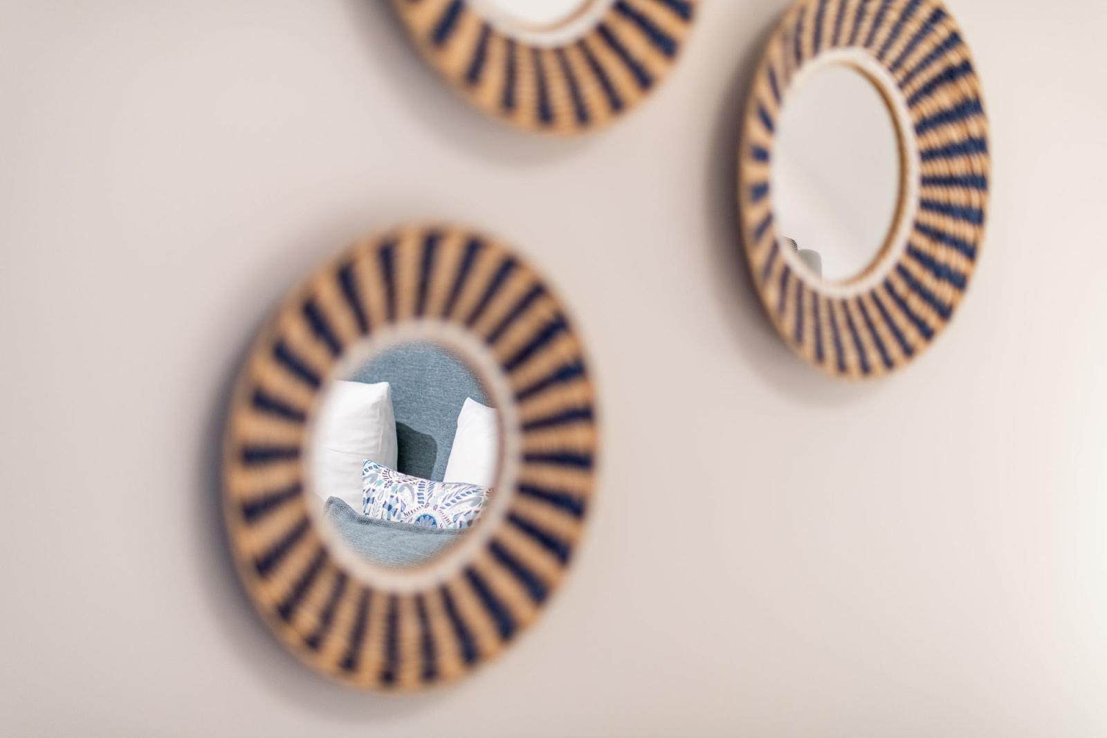 Wand mit drei runden Spiegeln mit geflochtenem Rahmen.