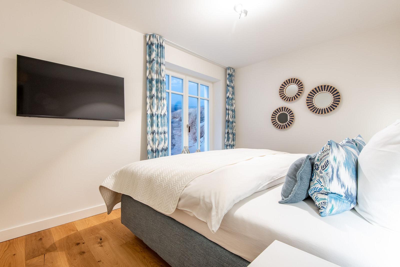 Schlafzimmer mit Bett, TV und Fenster zur Aussicht.