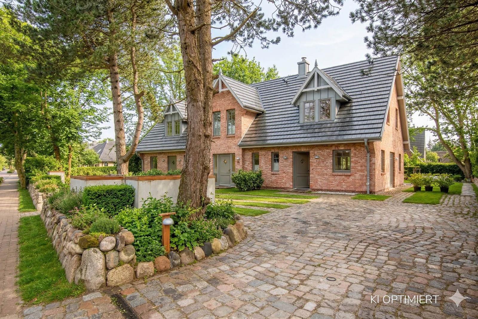 Zweistöckiges Haus mit Ziegelfassade und Schieferdach. Kiesweg und grüner Garten.
