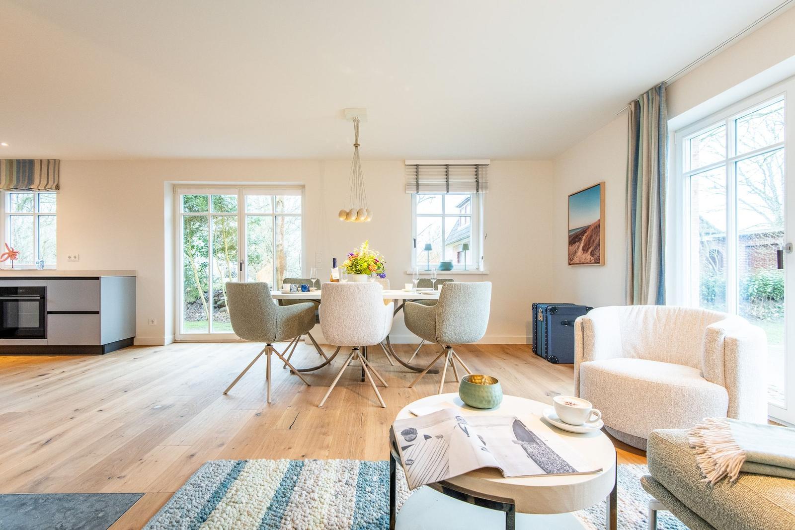 Wohn- und Essbereich mit Holzboden, Tisch, Stühlen und Fenstern.
