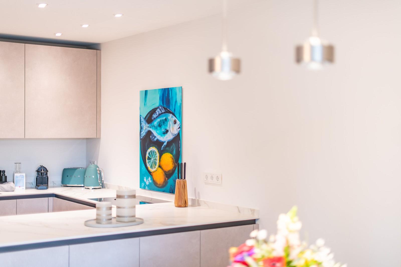 Küche mit moderner Ausstattung und Wandbild mit Fischmotiv.